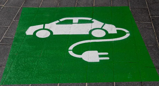 Grün markierter Ladeparkplatz mit weißem Symbol aus Auto und Ladestecker auf Pflastersteinen